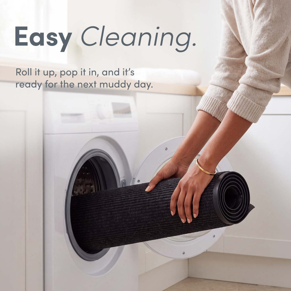 Hands rolling black mat into washing machine – Washable Doormat