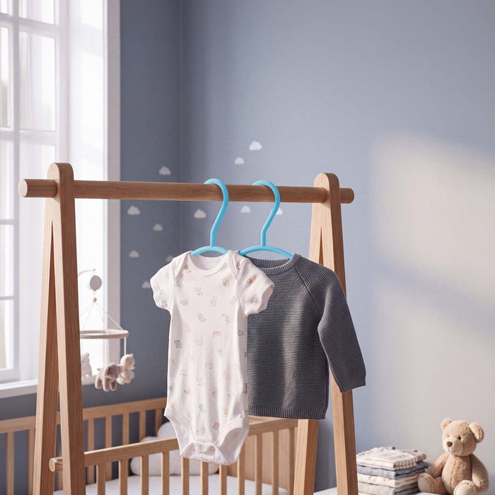 Teal nursery hangers holding a baby bodysuit and grey jumper on a clothes rail