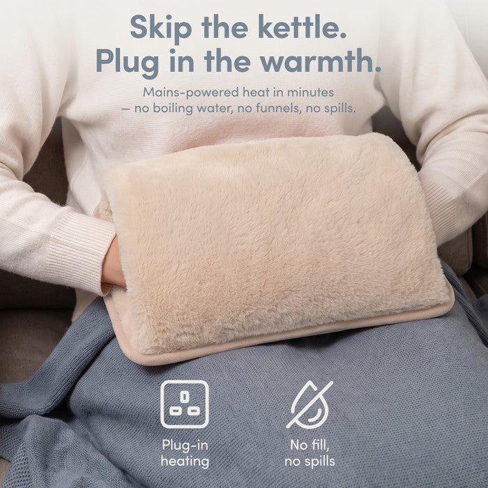 Cream rechargeable hot water bottle on lap, plug-in heat with no filling or spills