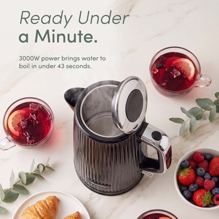 Black ribbed Keplin electric kettle with its lid open, showing the stainless steel interior, surrounded by cups of tea, berries and pastries, with text stating it boils water in under 43 seconds.