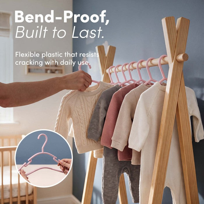Hand hanging a knitted baby jumper on a flexible bend-proof pink hanger