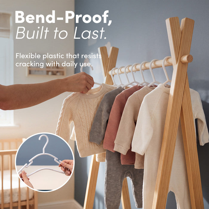 Hand hanging a knitted baby jumper on a flexible bend-proof nursery hanger
