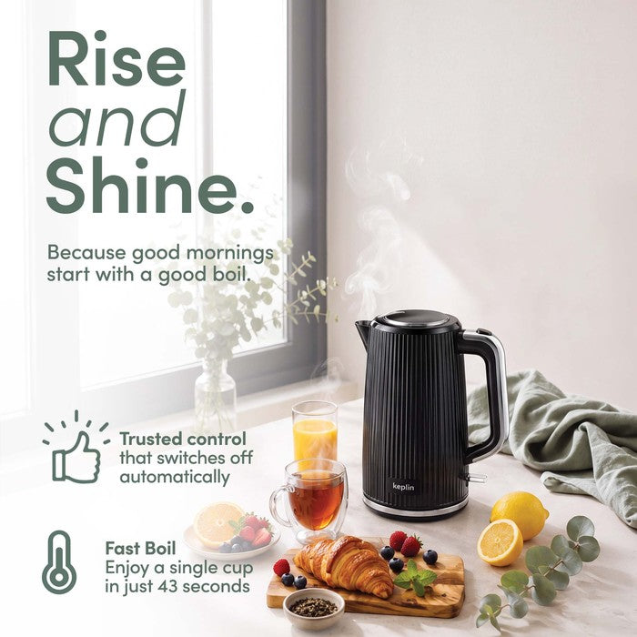 Black ribbed Keplin electric kettle beside a cup of tea, orange juice, croissants, berries and lemon on a bright breakfast table.