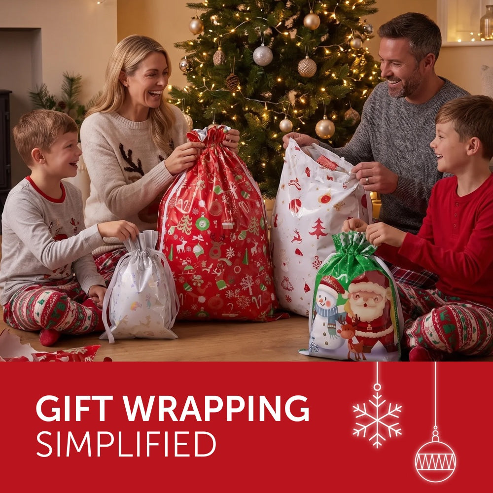 Family opening red, white and green festive foil gift bags by the Christmas tree