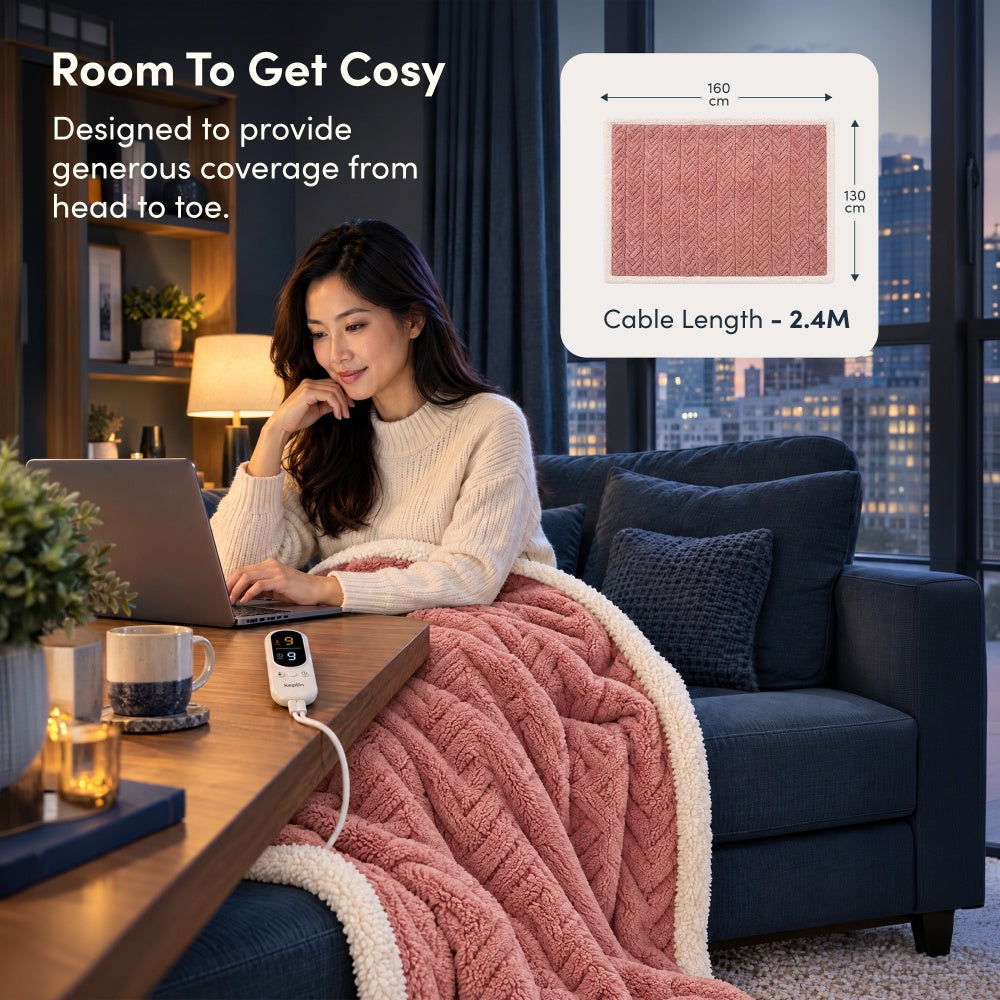 Woman on laptop under rose pink jacquard electric throw, 160 x 130cm size with 2.4m cable