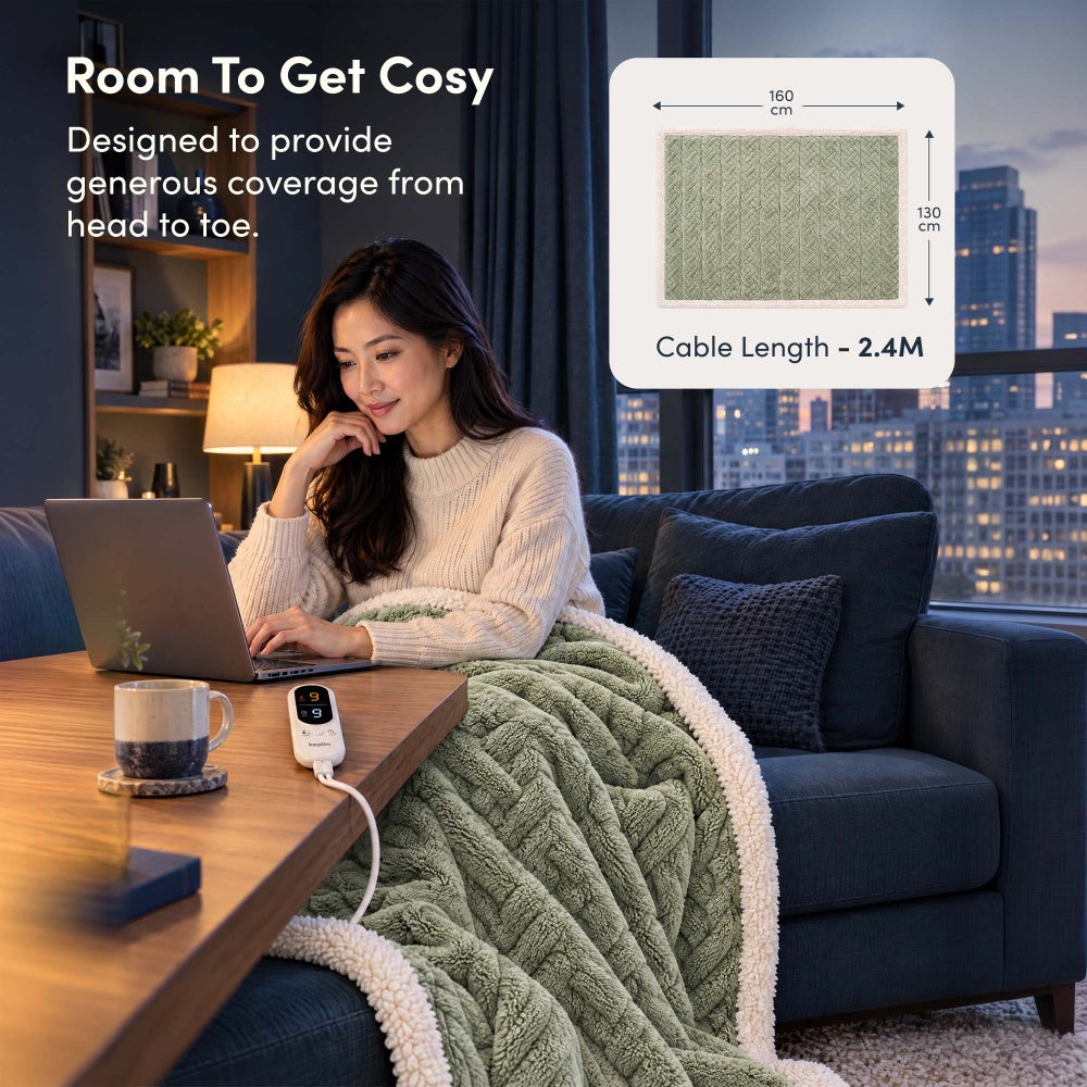 Woman on laptop under sage green jacquard electric throw, 160 x 130cm size with 2.4m cable