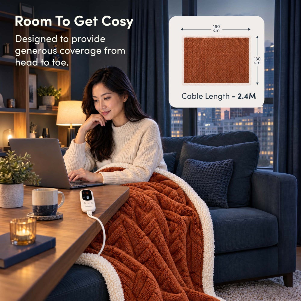 Woman on laptop under terracotta jacquard electric throw, 160 x 130cm size with 2.4m cable