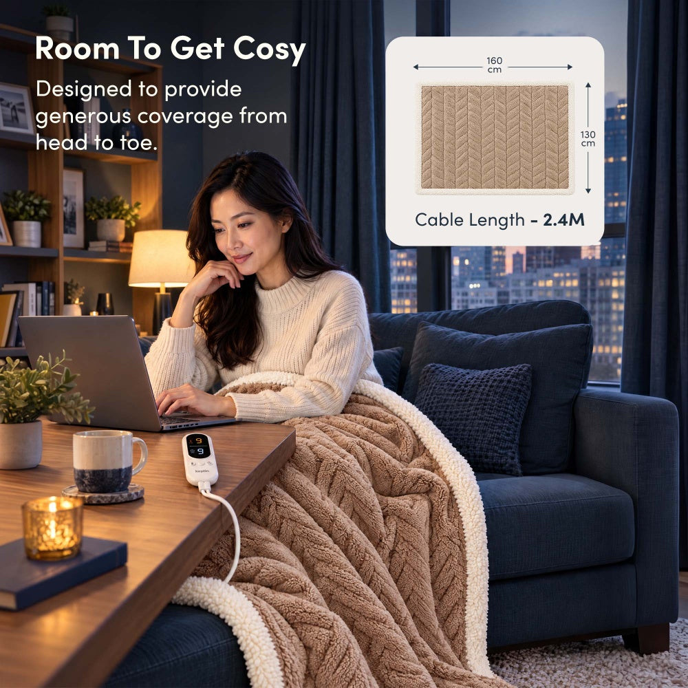 Woman on laptop under vanilla beige jacquard electric throw, 160 x 130cm size with 2.4m cable