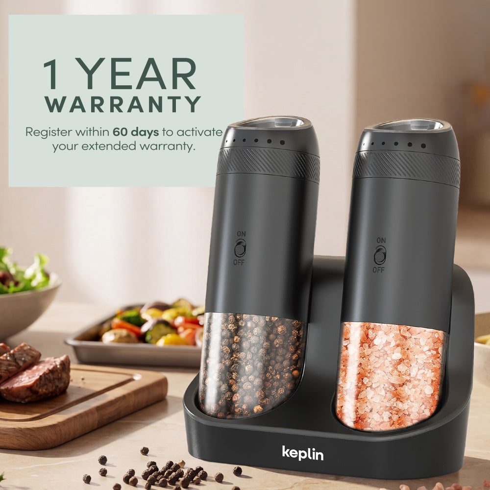 Two black gravity mills on their charging base beside steak and vegetables with a 1 year warranty badge