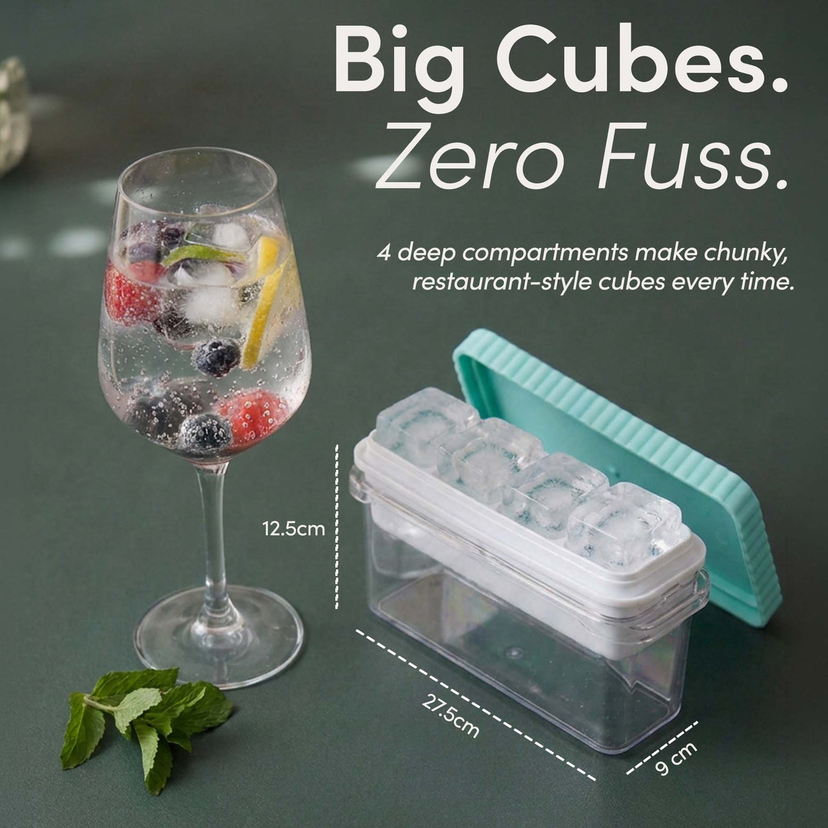 Large ice cube tray and bin measuring 27.5cm by 9cm by 12.5cm beside a glass of sparkling water with berries