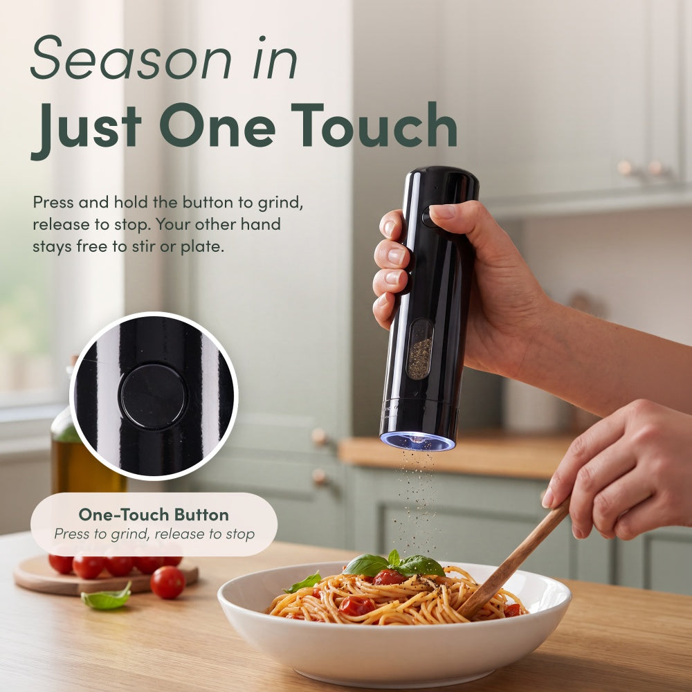 Hand pressing the one-touch button on the black mill to grind pepper onto pasta while the other hand stirs