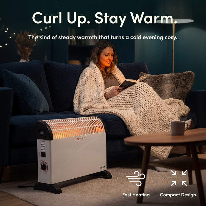 White convector heater warming living room while woman reads under a blanket