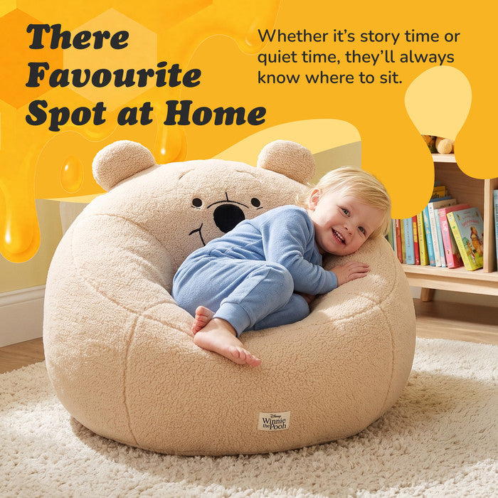 Toddler cuddling into the Winnie the Pooh plush snuggle chair at home
