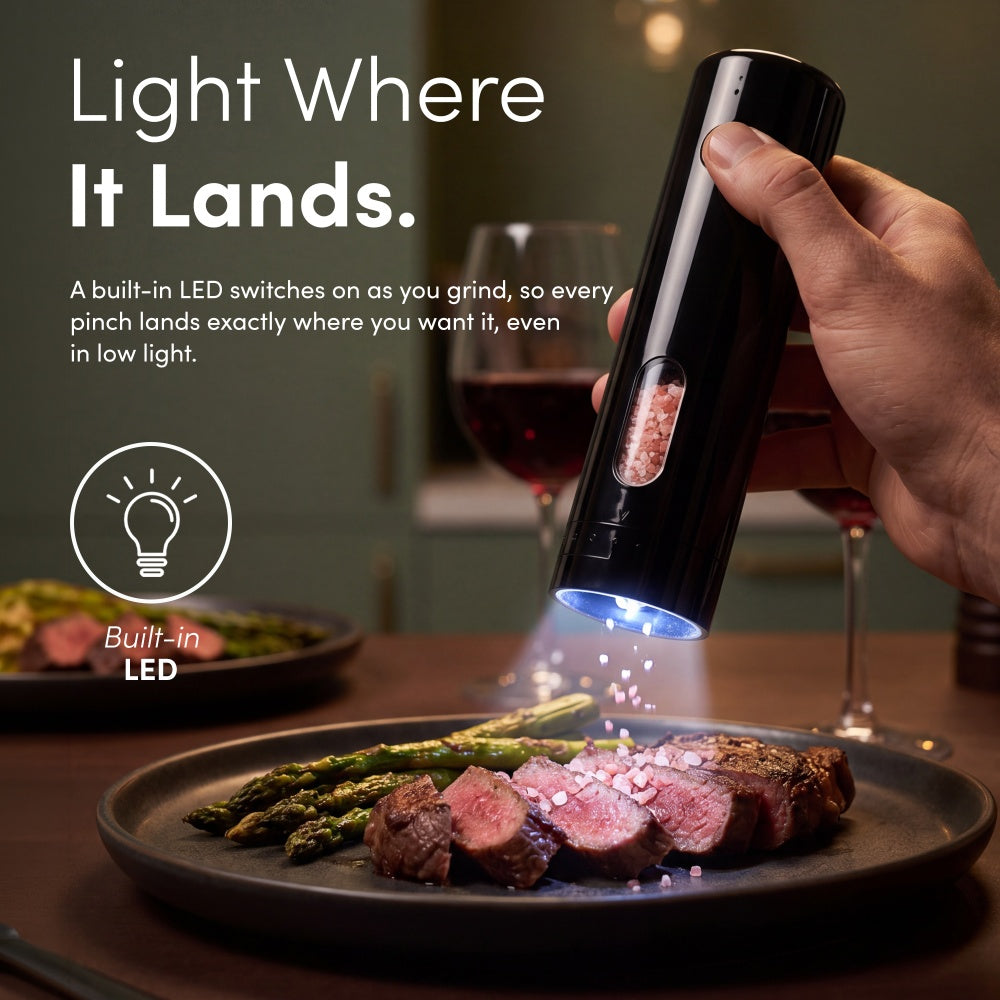 Black rechargeable mill with built-in LED lighting pink salt falling onto sliced steak and asparagus