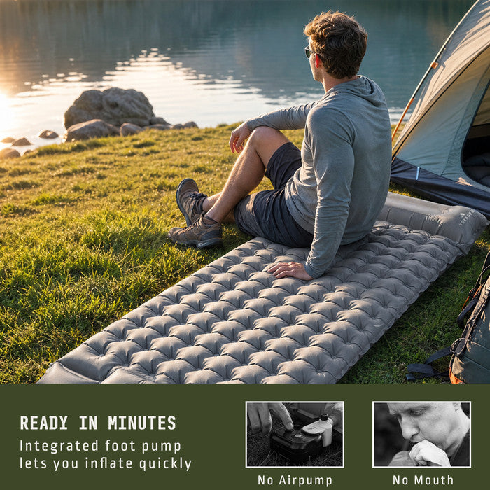 Man relaxing on Voyager grey inflatable camping mat by lakeside tent