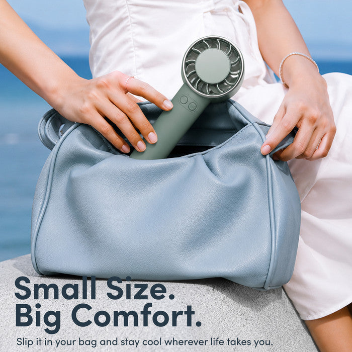 Haze green mini portable fan being placed into handbag – compact travel size