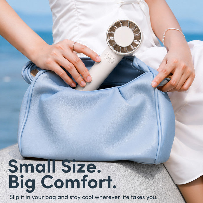 Cream mini portable fan being placed into handbag – compact travel size