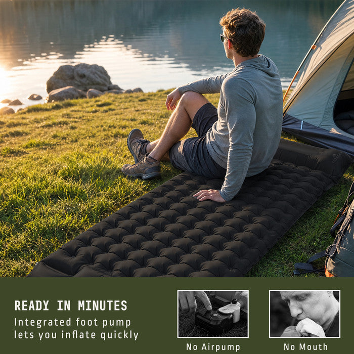 Man relaxing on Voyager black inflatable camping mat by lakeside tent