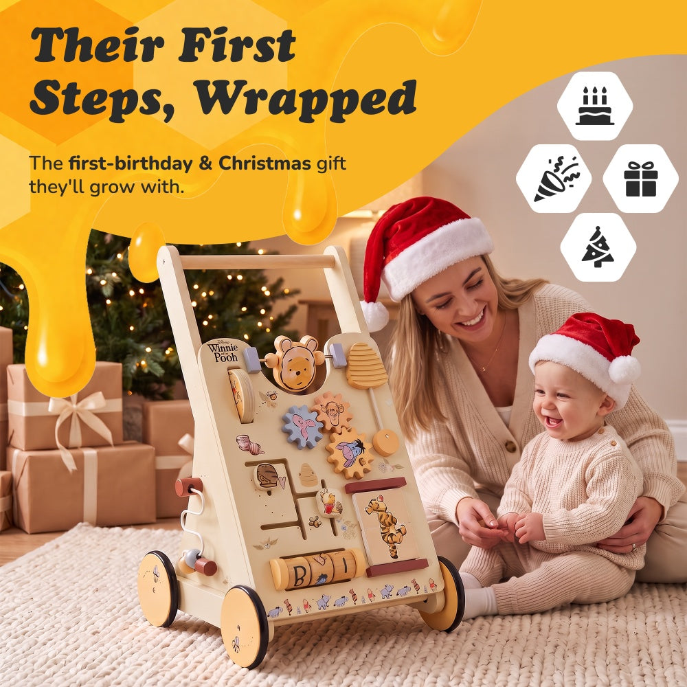 Parent and baby in Santa hats beside the Winnie the Pooh wooden walker as a first birthday or Christmas gift
