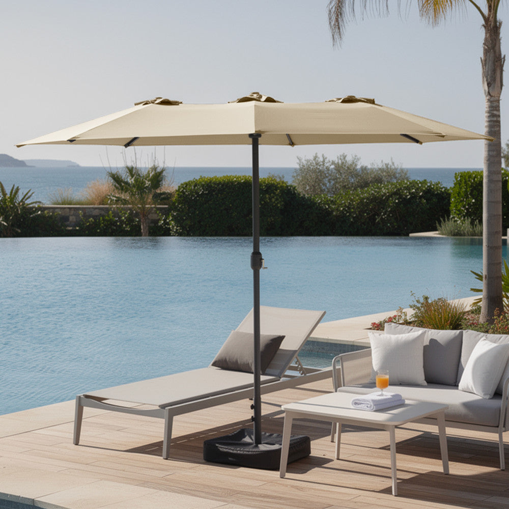 Cream double garden parasol open over modern outdoor sofa set on a patio with lush garden
