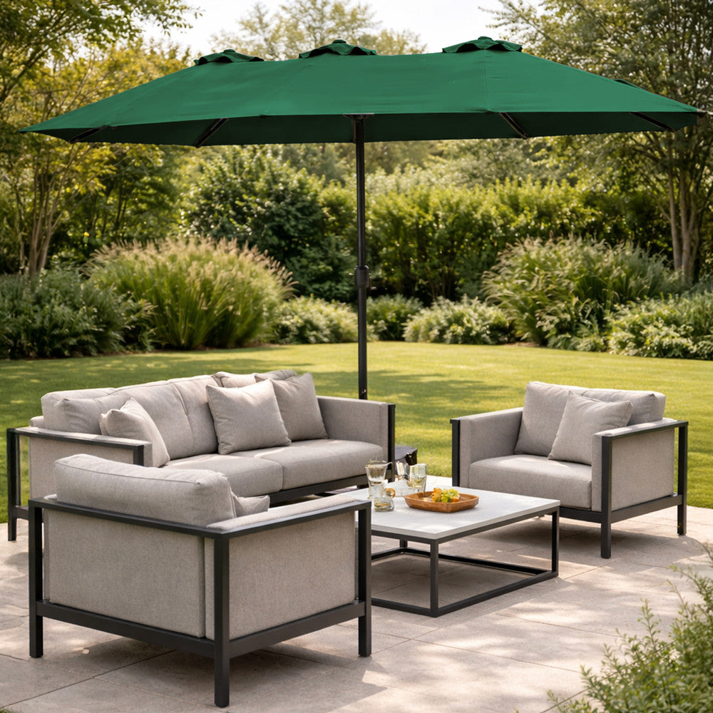 Green double garden parasol open over modern outdoor sofa set on a patio with lush garden