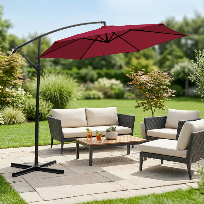 Burgundy 3m cantilever garden parasol over rattan garden lounge set on a patio with lush garden backdrop
