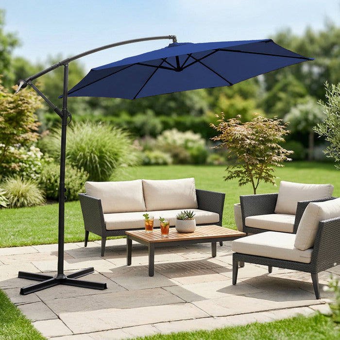 Navy blue 3m cantilever garden parasol over rattan garden lounge set on a patio with lush garden backdrop